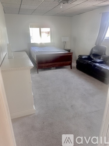 A bedroom with a bed, a chair, and a nightstand.