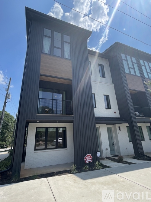 A modern two-story house with a black and white exterior is for sale.