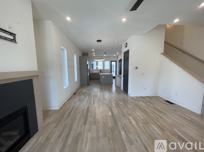 A spacious living room with wood flooring and a fireplace.
