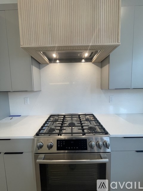 A modern kitchen with a stove top oven and white cabinets.