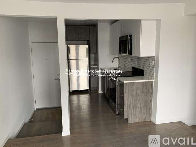 A kitchen with a refrigerator, sink, and cabinets.