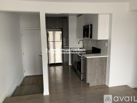 A kitchen with a refrigerator, sink, and cabinets.