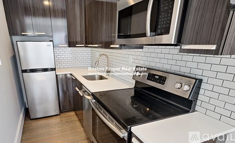 A modern kitchen with a stainless steel refrigerator, microwave, and oven.