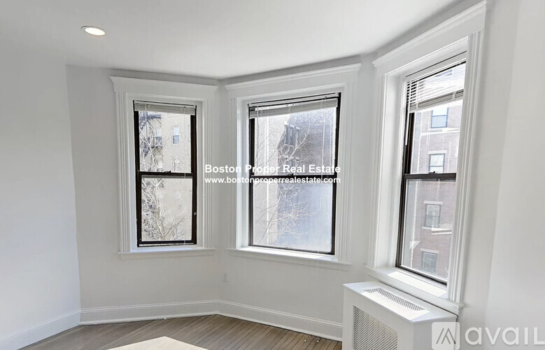 A room with three windows and a radiator on the wall.