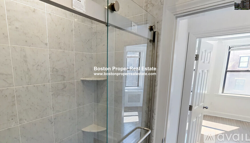A bathroom with a glass shower door and a white door.