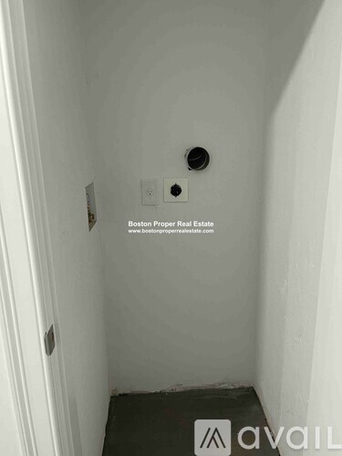 A small, white, enclosed space with a door and a hole in the wall.