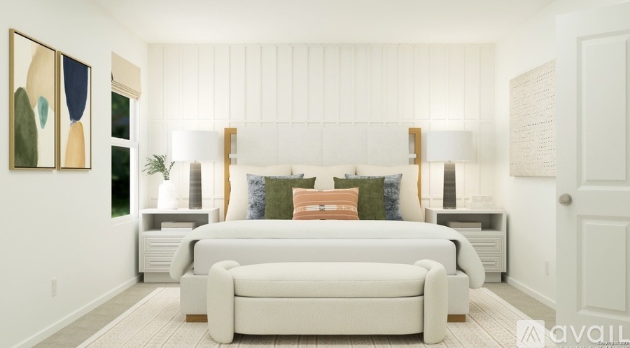 A white bedroom with a bed, couch, and artwork on the wall.