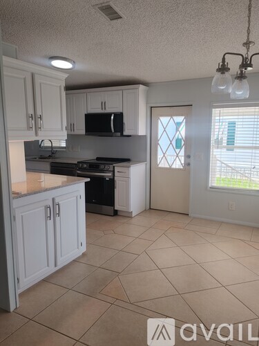 A kitchen with white cabinets and a tiled floor.