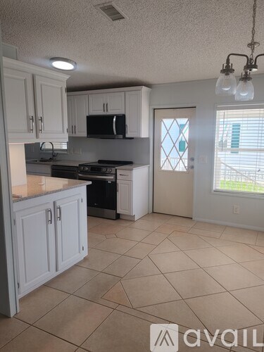 A kitchen with white cabinets and a tiled floor.