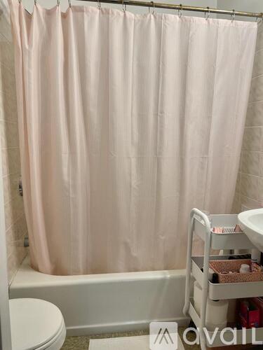 A pink shower curtain in a bathroom.