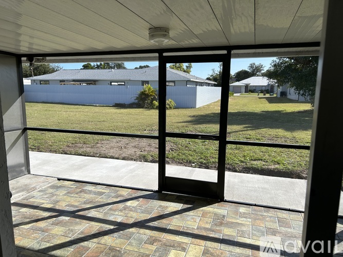 A view from inside a building looking out through a glass door to a white building and a green lawn.