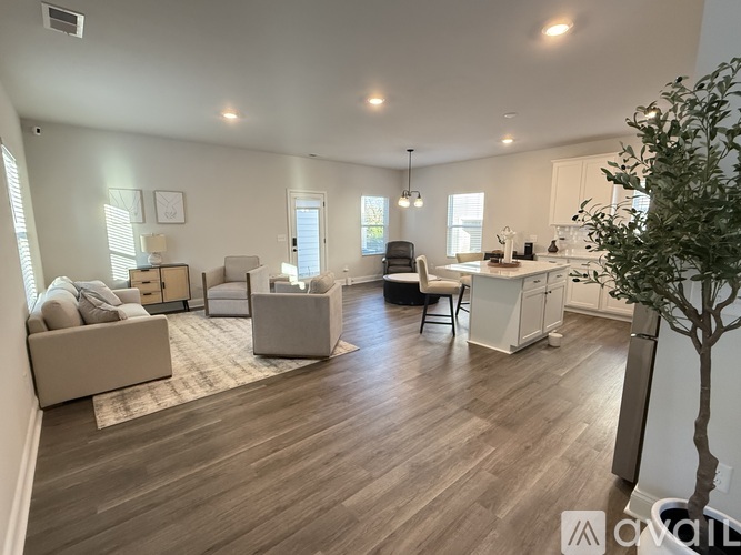 A well-lit, spacious living room with a kitchen area in the background.