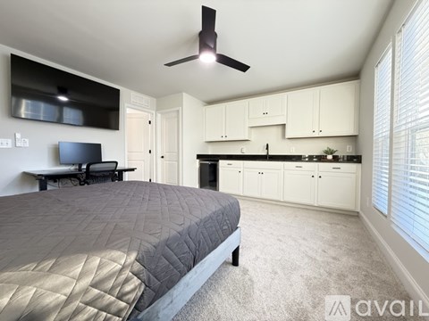 A bedroom with a large bed and a television mounted on the wall.