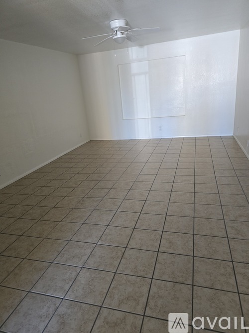 A room with a fan and tile flooring.