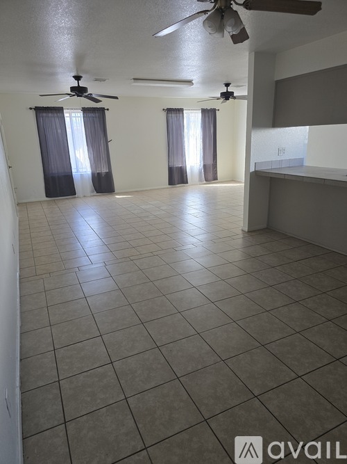 A spacious room with tiled flooring and ceiling fans.