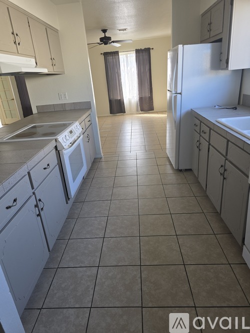 A kitchen with white cabinets and a tile floor.