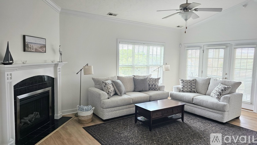 A living room with a fireplace, two couches, a coffee table, and a ceiling fan.