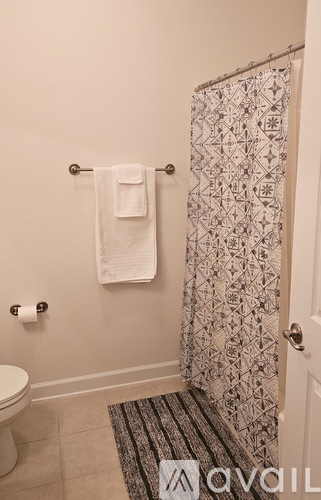 A bathroom with a toilet, a towel, and a shower curtain.