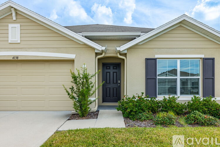 A beige house with a black door and a window with black shutters.