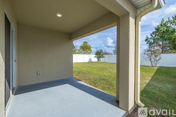A patio area with a view of a grassy field and trees.