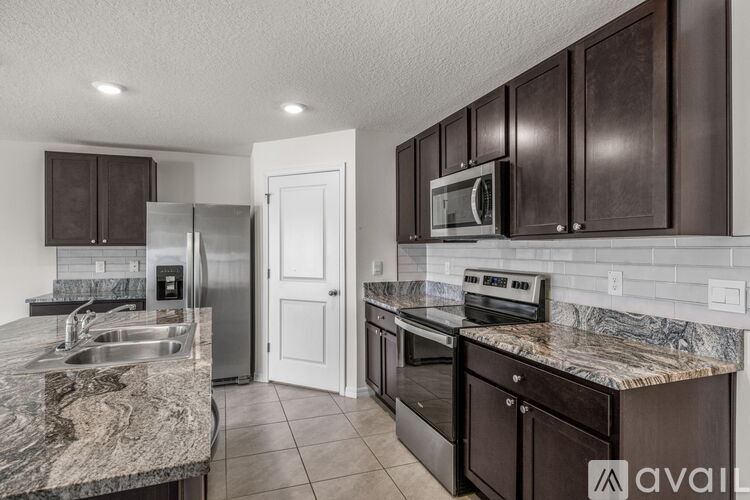 A kitchen with dark brown cabinets and granite countertops.