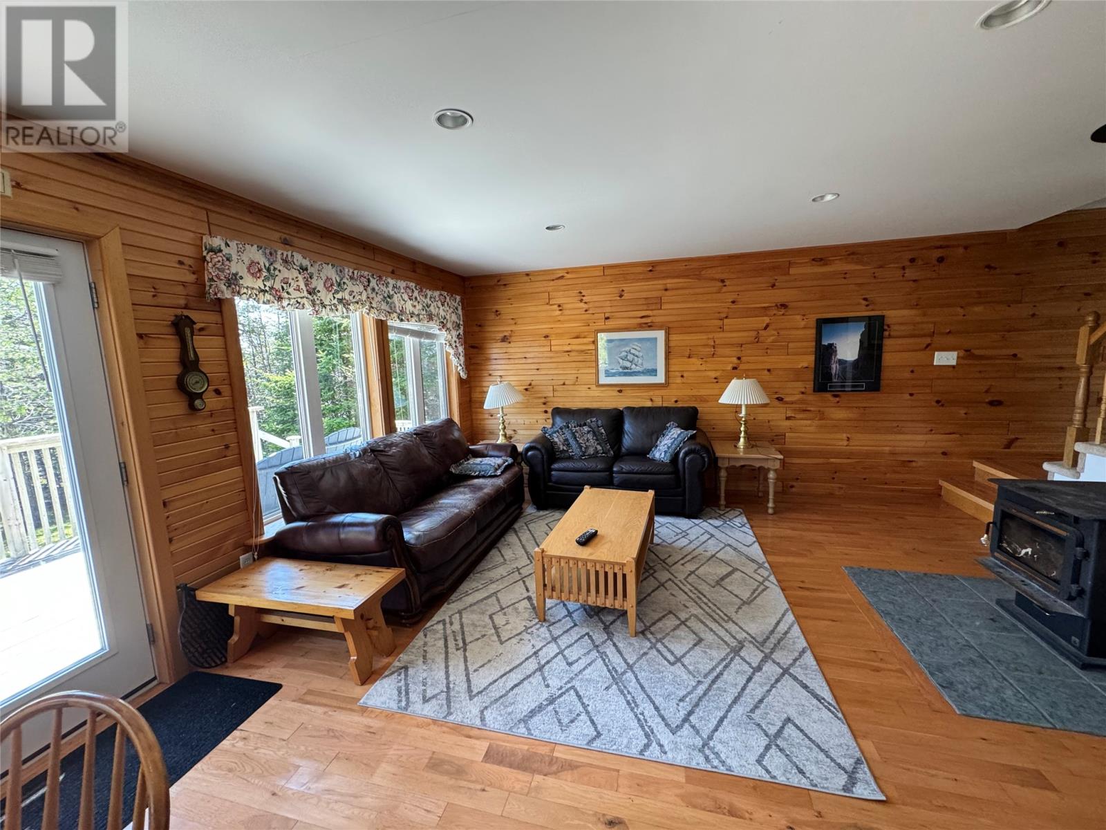 A living room with a black couch and wooden floors.