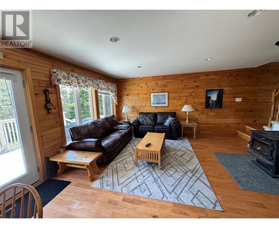 A living room with a black couch and wooden floors.