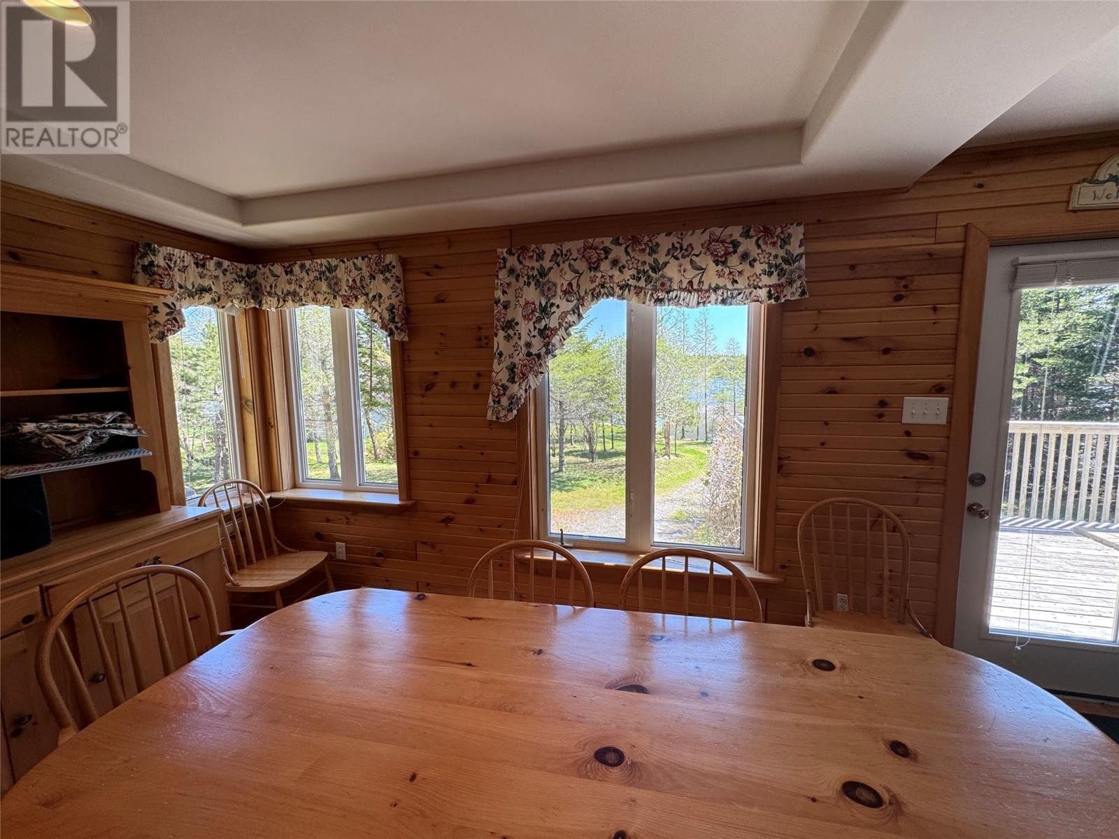 A wooden dining room with a large table and chairs.