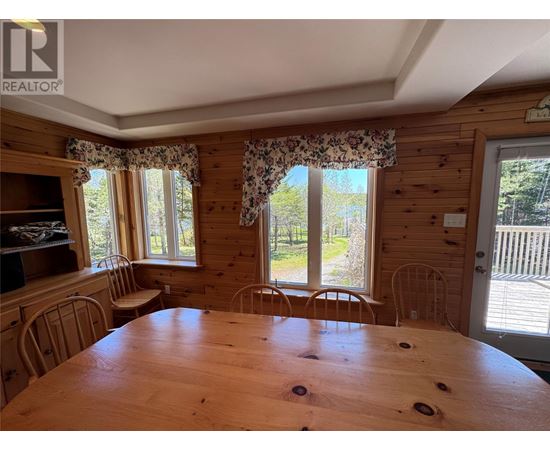 A wooden dining room with a large table and chairs.