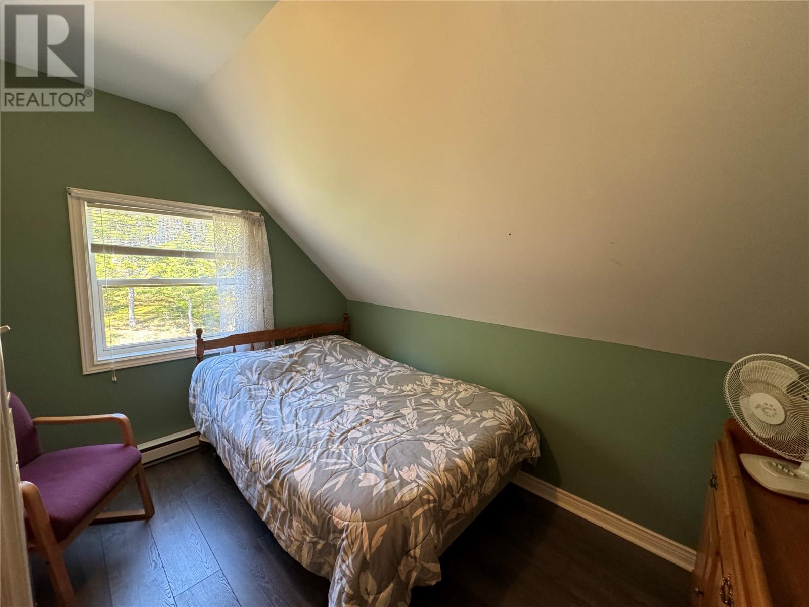 A bedroom with a bed, chair, and window.