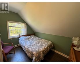 A bedroom with a bed, chair, and window.