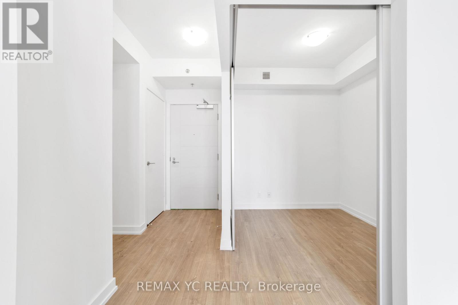 A white room with a wooden floor and a doorway leading to another room.