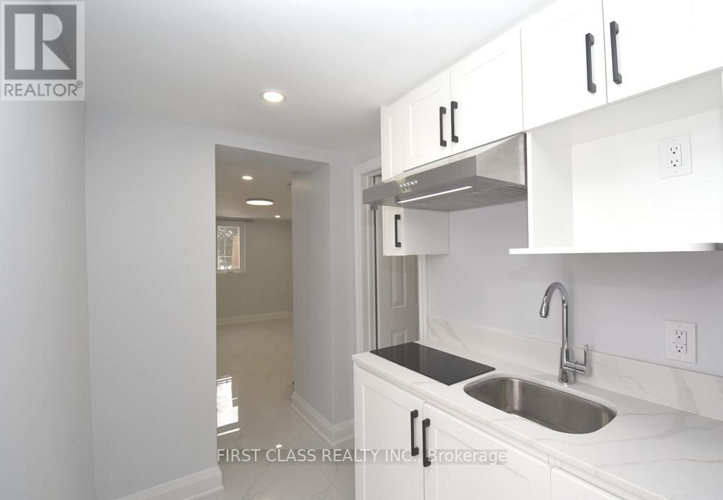 A kitchen with white cabinets and a stainless steel sink.