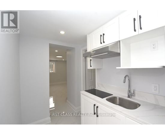 A kitchen with white cabinets and a stainless steel sink.