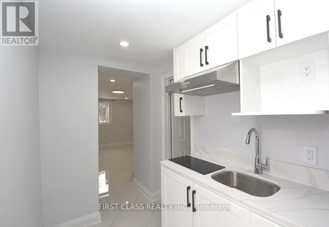 A kitchen with white cabinets and a stainless steel sink.