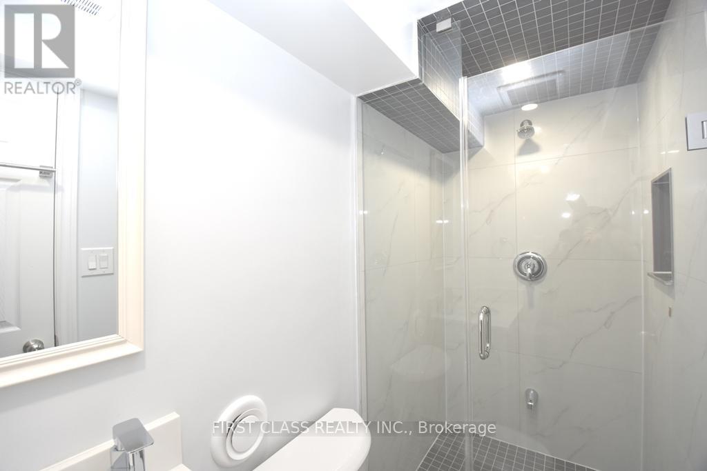 A white bathroom with a glass shower stall and a mirror above the sink.