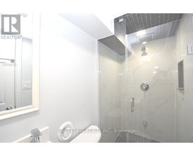 A white bathroom with a glass shower stall and a mirror above the sink.