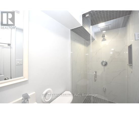 A white bathroom with a glass shower stall and a mirror above the sink.