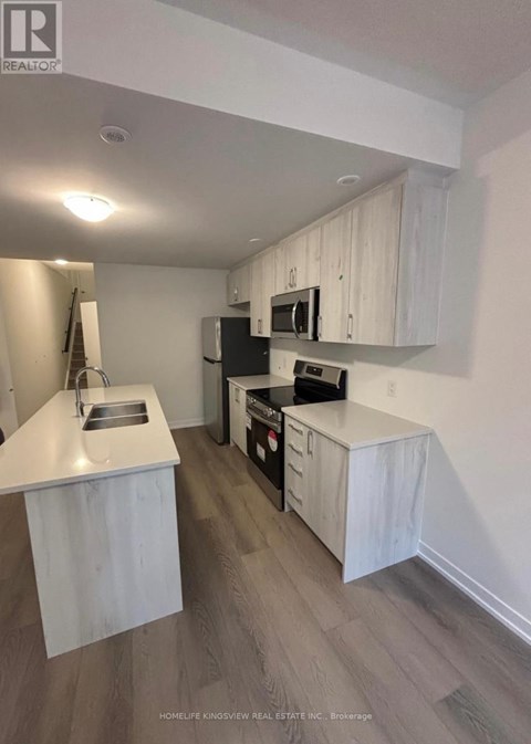 A kitchen with white cabinets and a black refrigerator.