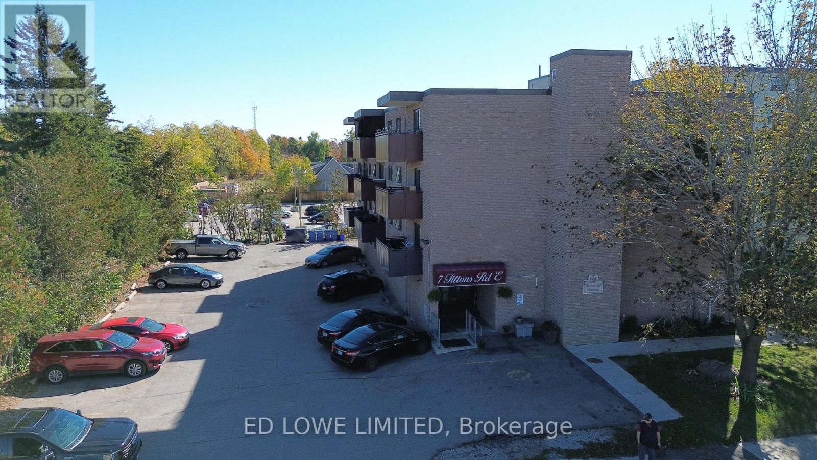 A parking lot with cars and a building with a sign that says "ED LOWE LIMITED, Brokerage".