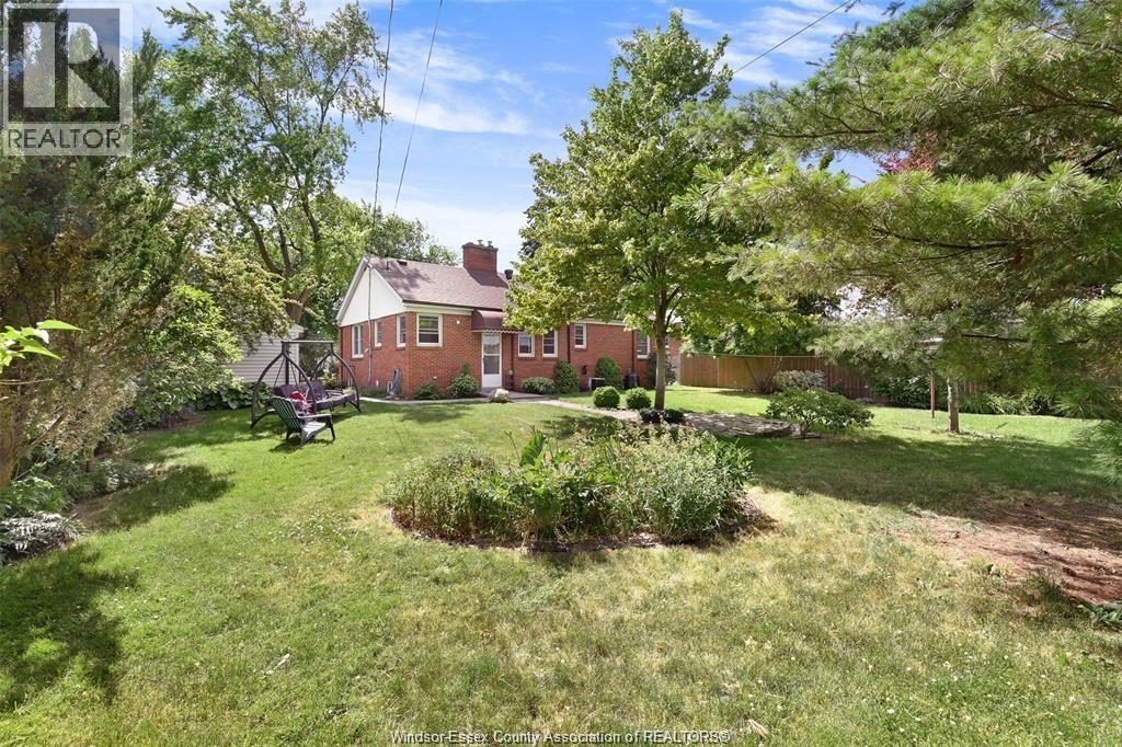 A red brick house with a green lawn and trees.