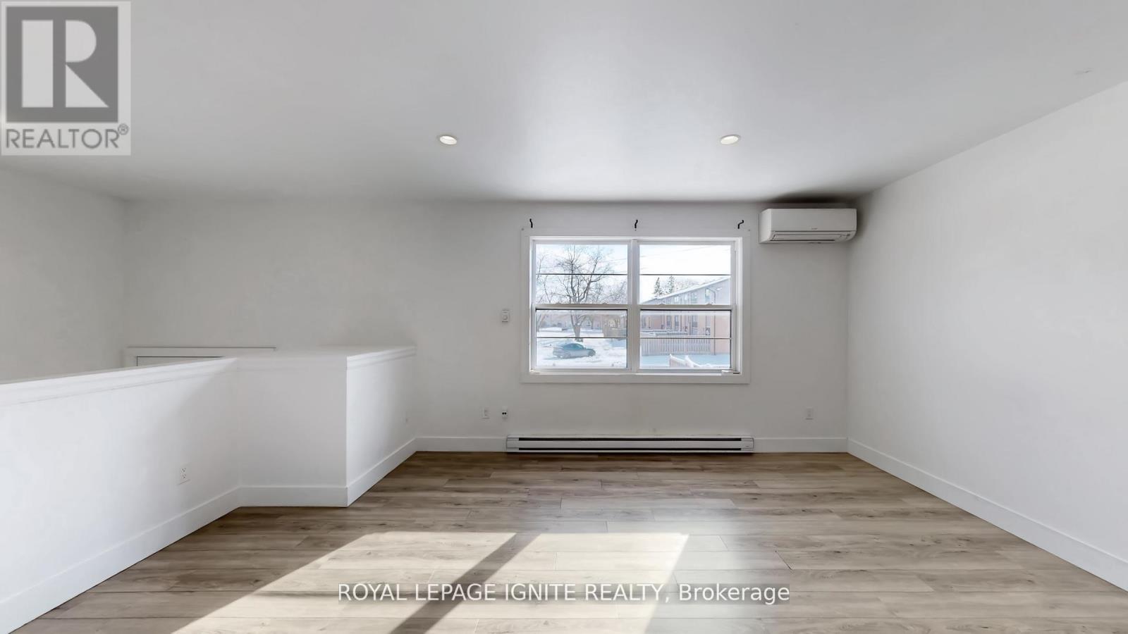 A spacious room with a window and a wooden floor.