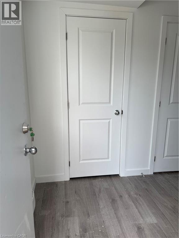 A white door with a silver handle is in a room with wooden flooring.