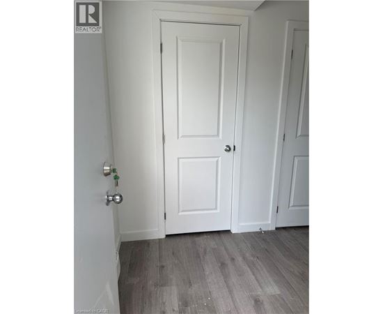 A white door with a silver handle is in a room with wooden flooring.