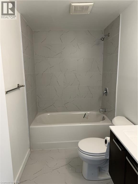 A white toilet sits in a bathroom with a bathtub and a shower.