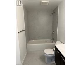 A white toilet sits in a bathroom with a bathtub and a shower.