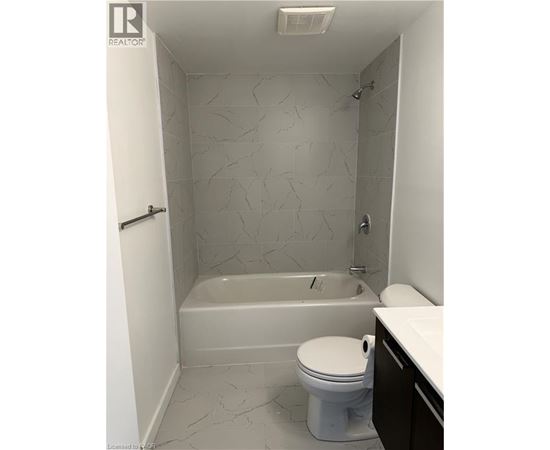 A white toilet sits in a bathroom with a bathtub and a shower.