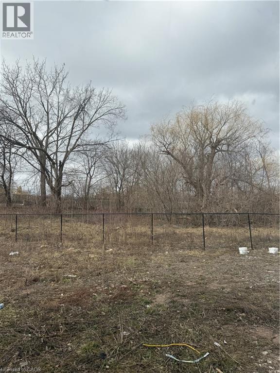 A field with a fence and trees in the background.
