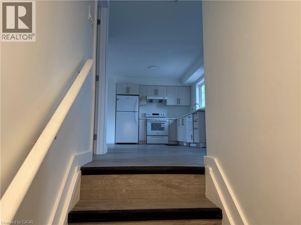 A hallway with a staircase leading to a kitchen area.