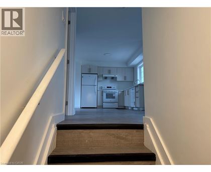 A hallway with a staircase leading to a kitchen area.